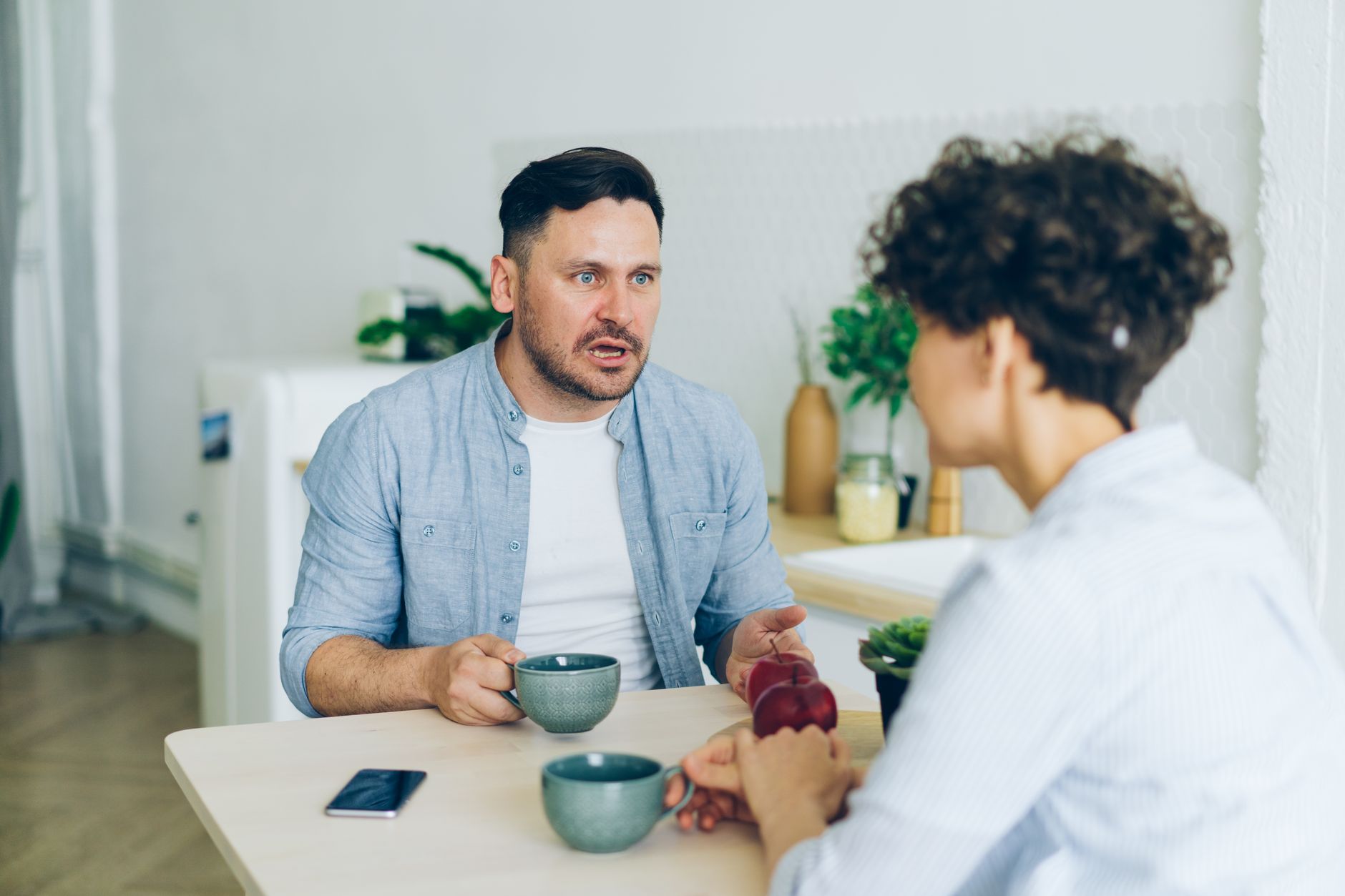 Een stel voert een serieus gesprek aan de keukentafel met koffiekopjes
