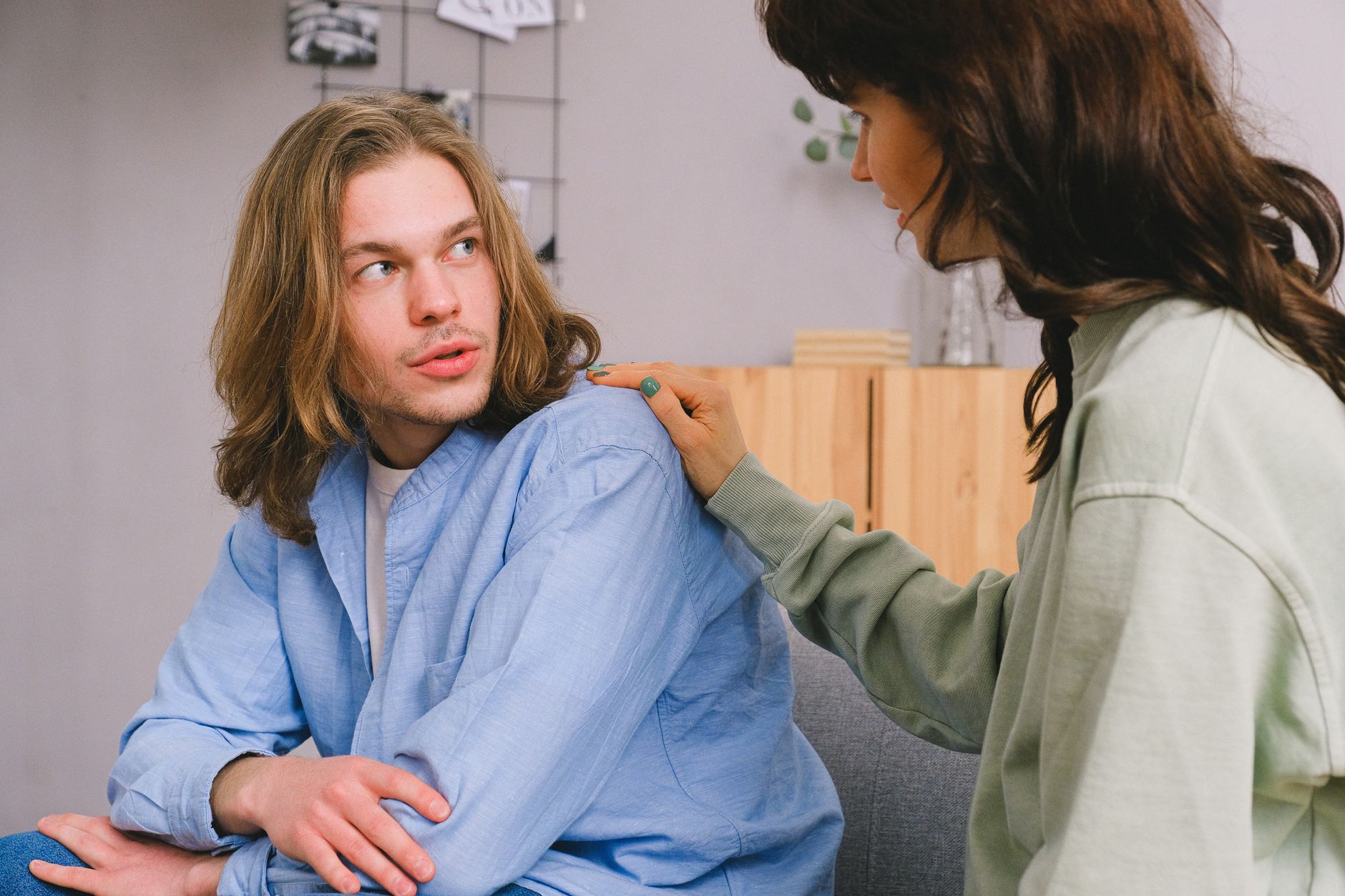 Een vrouw praat met haar partner en legt een hand op zijn schouder